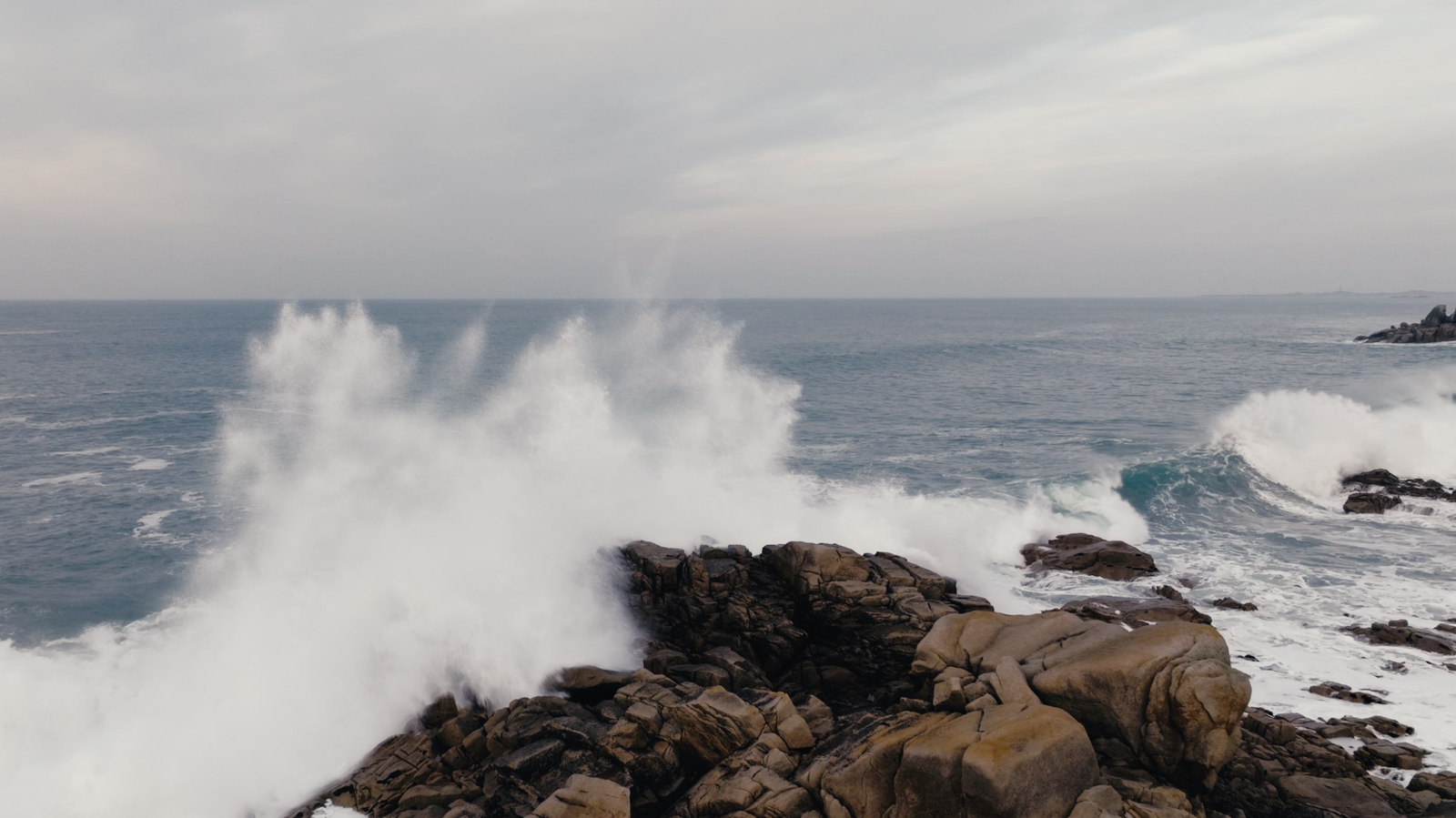 Vague qui se brise sur des rochers en bord de mer, vue au drone, Bretagne